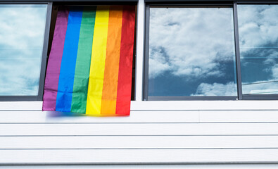 LGBTQIA+ rainbow flag hanging on house window on pride month