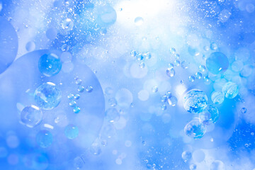 Small air bubbles in a bottle immersed in the sea. Blue abstract background. Illuminated liquid surface. Macro photo.