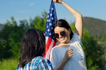 Two smiling asian woman outdoors waving USA flag, celebration of patriotic american national holiday 4th of july independence day