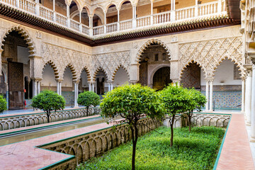 Naklejka premium Beautiful formal public garden inside Alcazar Seville palace in summertime in Andalusia