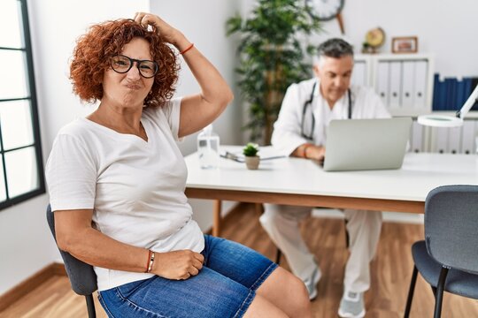 Senior woman sitting at doctor appointment confuse and wonder about question. uncertain with doubt, thinking with hand on head. pensive concept.