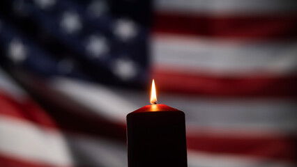 Burning candle against the background of the waving flag of the united states of america in the...