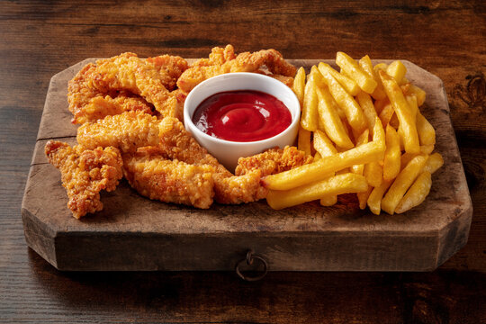 Battered chicken wedges, crispy nuggets, with a bbq sauce on a wooden table, American fast food