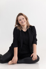 Vertical studio portrait of smiling and plump young woman sitting on knees on white back view. Natural body. Self esteem