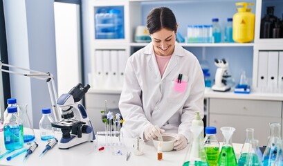 Fototapeta premium Young woman wearing scientist uniform working at laboratory