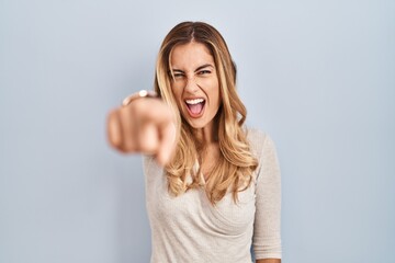 Fototapeta na wymiar Young blonde woman standing over isolated background pointing displeased and frustrated to the camera, angry and furious with you