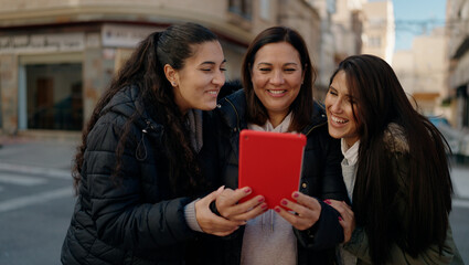 Mother and daugthers using touchpad hugging each other at street