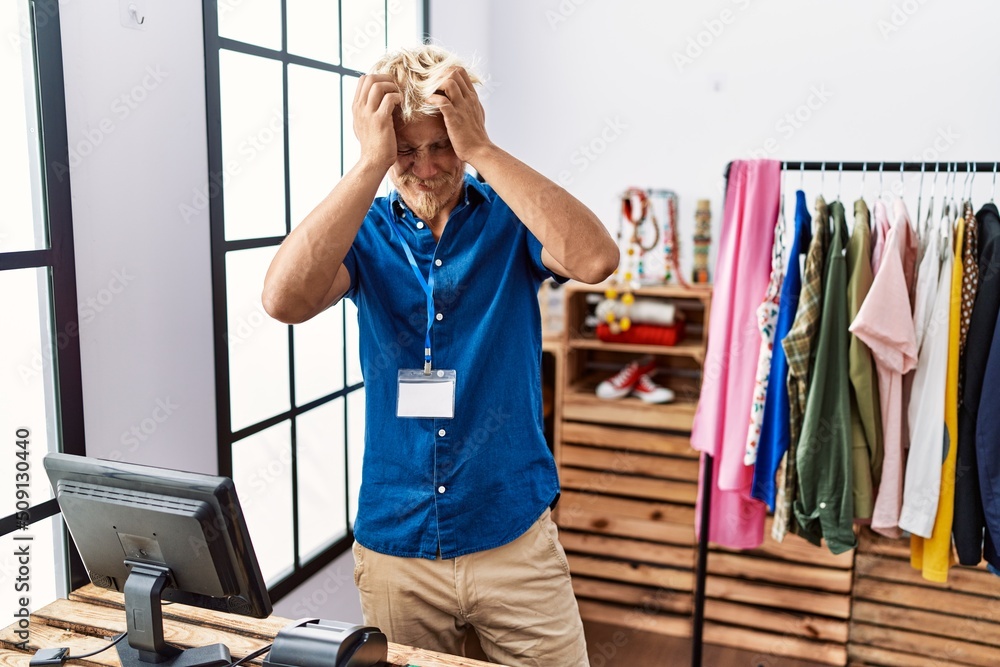 Sticker young blond man working as manager at retail boutique suffering from headache desperate and stressed