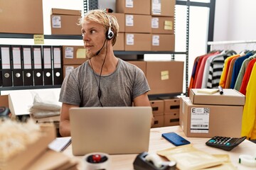 Young blond man wearing operator headset working at online shop looking to side, relax profile pose with natural face with confident smile.