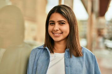 Young latin girl smiling happy standing at the city.