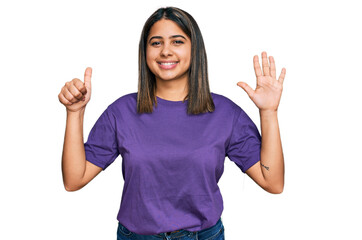 Young hispanic girl wearing casual purple t shirt showing and pointing up with fingers number six while smiling confident and happy.