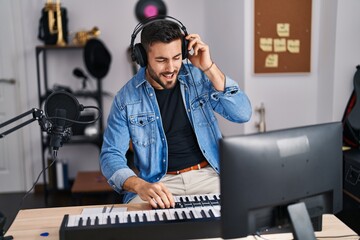 Fototapeta na wymiar Young hispanic man artist smiling confident having video call at music studio