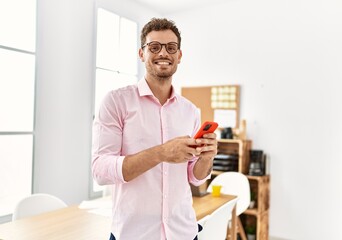 Young hispanic man smiling confident using smartphone at office
