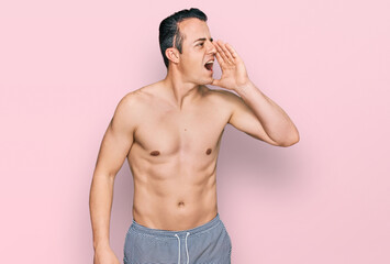 Fototapeta premium Handsome young man wearing swimwear shirtless shouting and screaming loud to side with hand on mouth. communication concept.
