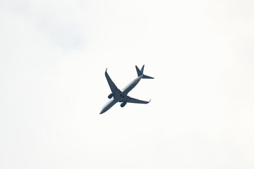 Airplane flying above in cloudy sky. Air transport concept