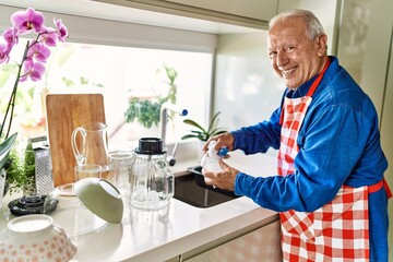 Senior man smiling confident washing glass at kitchen