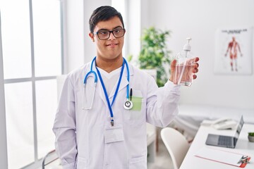 Down syndrome man wearing doctor uniform holding sanitizer gel hands at clinic