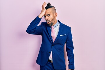 Young hispanic man wearing business suit and tie surprised with hand on head for mistake, remember error. forgot, bad memory concept.