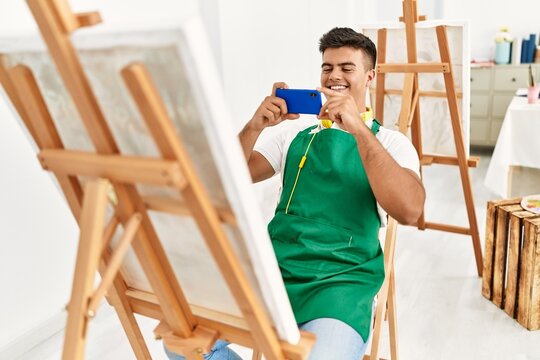 Young hispanic man smiling confident make photo to draw canvas at art studio