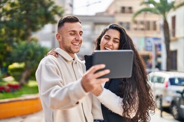 Fototapeta premium Man and woman smiling confident using touchpad at park