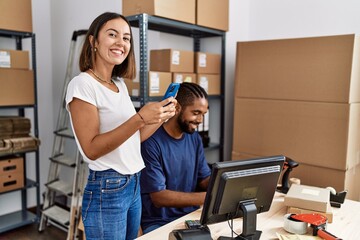 Man and woman business partners using smartphone and packing order at storehouse