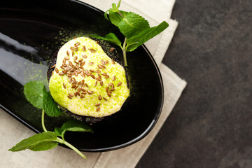 Tasty chocolate brownie with cherry and banana cream on black plate.