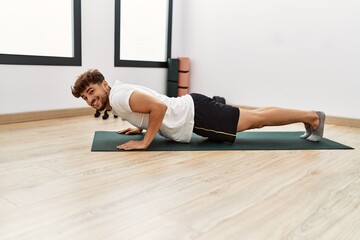 Young arab man smiling confident training abs exercise at sport center