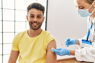Fototapeta premium Young arab man smiling happy waiting for covid-19 vaccine at hospital.