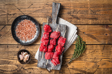 Raw beef shish kebab, Meat with spices and herbs on Skewers. Wooden background. Top view