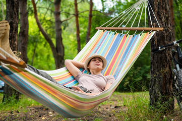 Caucasian woman lies in a hammock in a pine forest
