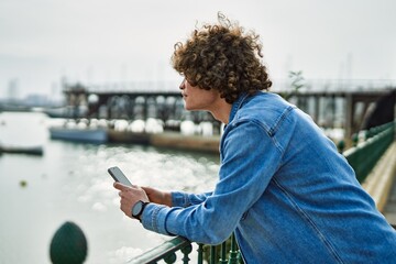 Obraz premium Young hispanic man using smartphone at marina port