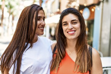 Fototapeta premium Two latin girls smiling happy and hugging at the city.