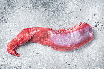 Whole piece of raw beef tenderloin on butcher table. Gray background. Top view