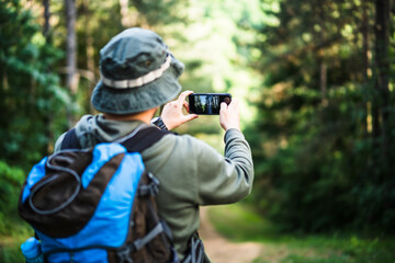Image of man enjoys hiking and making pictures  with his phone. © inesbazdar