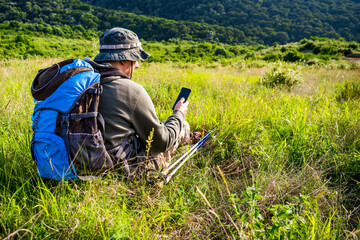 Image of hiker using phone while spending time in nature.	