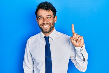Handsome man with beard wearing business shirt and tie smiling with an idea or question pointing...