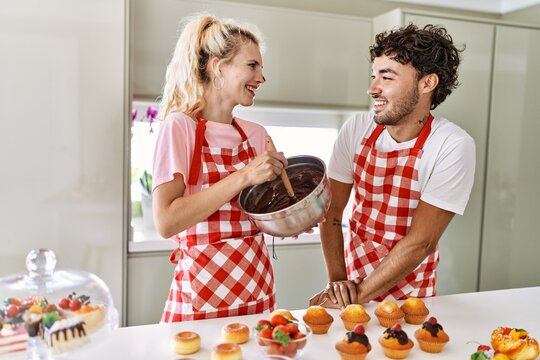 Young couple smiling happy cooking sweets at kitchen.