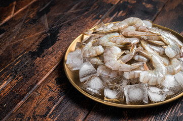Fresh Raw tiger white shrimp prawn peeled with tail on ice. Wooden background. Top view. Copy space