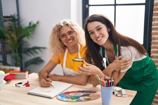 Two women artists drinking coffee drawing at art studio