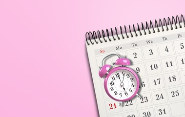Pink alarm clock and calendar on a background. Concept days of menstruation or menopause.