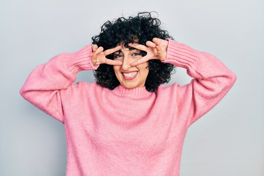 Young middle east woman wearing casual clothes doing peace symbol with fingers over face, smiling cheerful showing victory