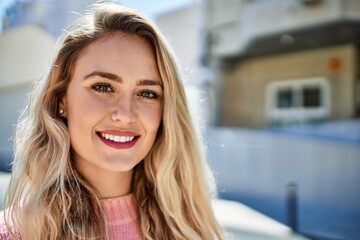 Young blonde woman smiling at the city
