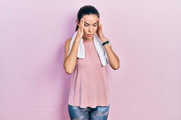 Young brunette woman wearing sportswear and towel with hand on head for pain in head because...
