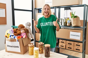 Young caucasian woman wearing volunteer t shirt at donations stand success sign doing positive...
