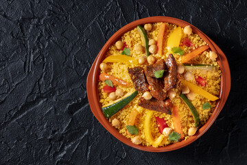 Moroccan couscous with meat, traditional festive dinner, shot from the top on a black background with copy space - obrazy, fototapety, plakaty