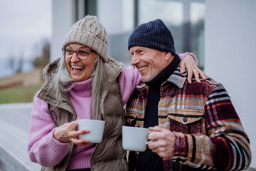 Happy senior couple sitting on terrace and drinking coffee together.