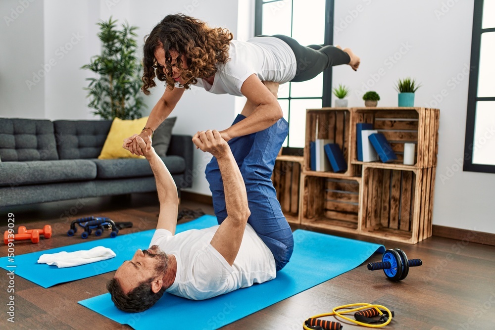 Sticker Middle age hispanic couple smiling happy doing acro sport at home.