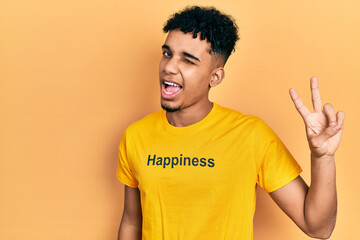 Young african american man wearing t shirt with happiness word message smiling with happy face...