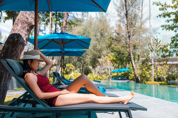Happy asian woman in red swimsuit and a straw hat relaxing on chair beach at Koh Mak, Phangnga,...