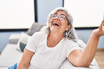 Middle age woman sitting on sofa speaking at home